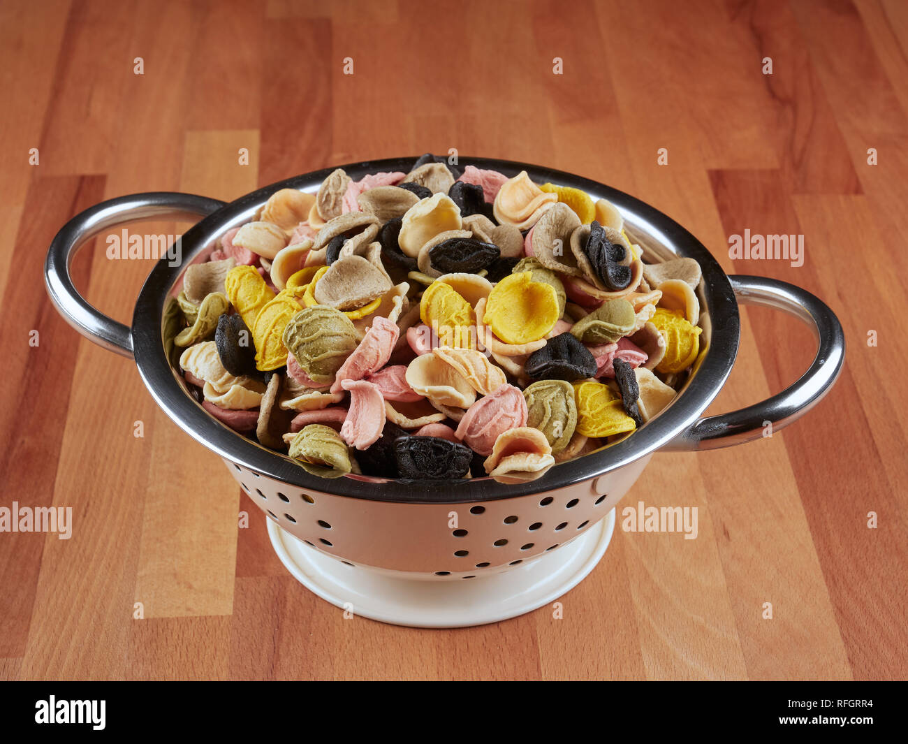 Colorful uncooked orecchiette pasta in a small colander Stock Photo
