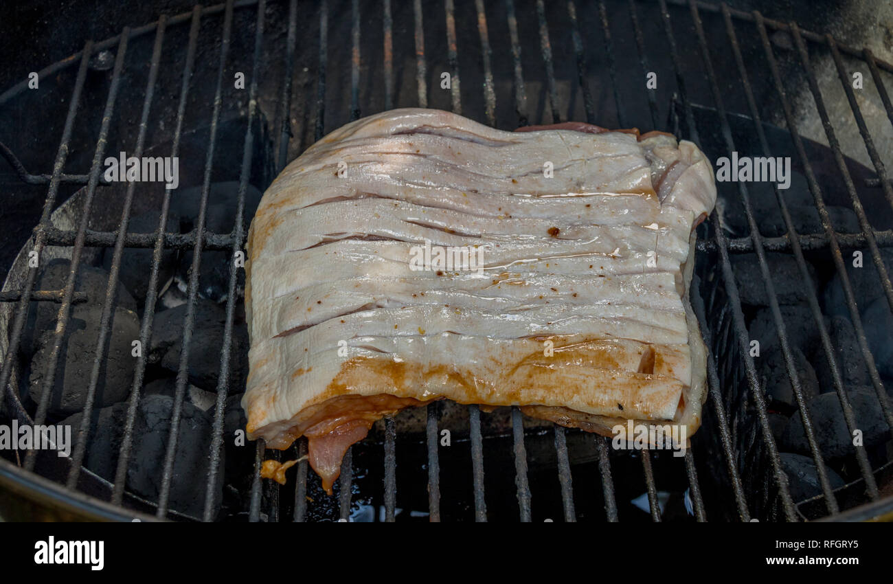 Raw seasoned red meat placed on the grill in an outdoor kettle oven image with copy space in landscape format Stock Photo