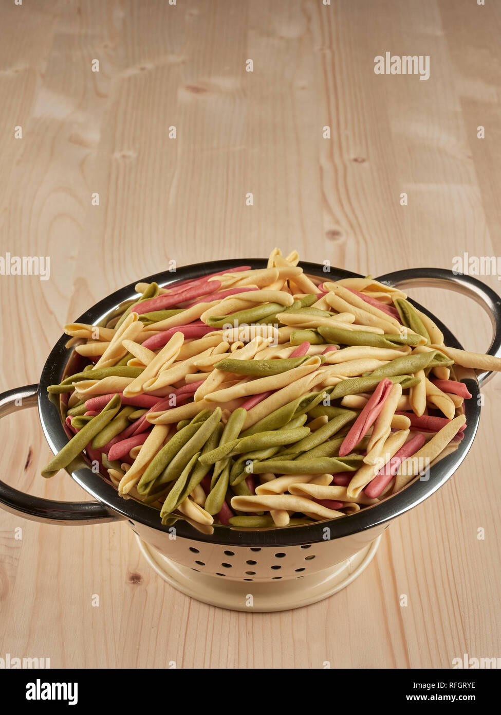 Colorful uncooked orecchiette pasta in a small colander Stock Photo