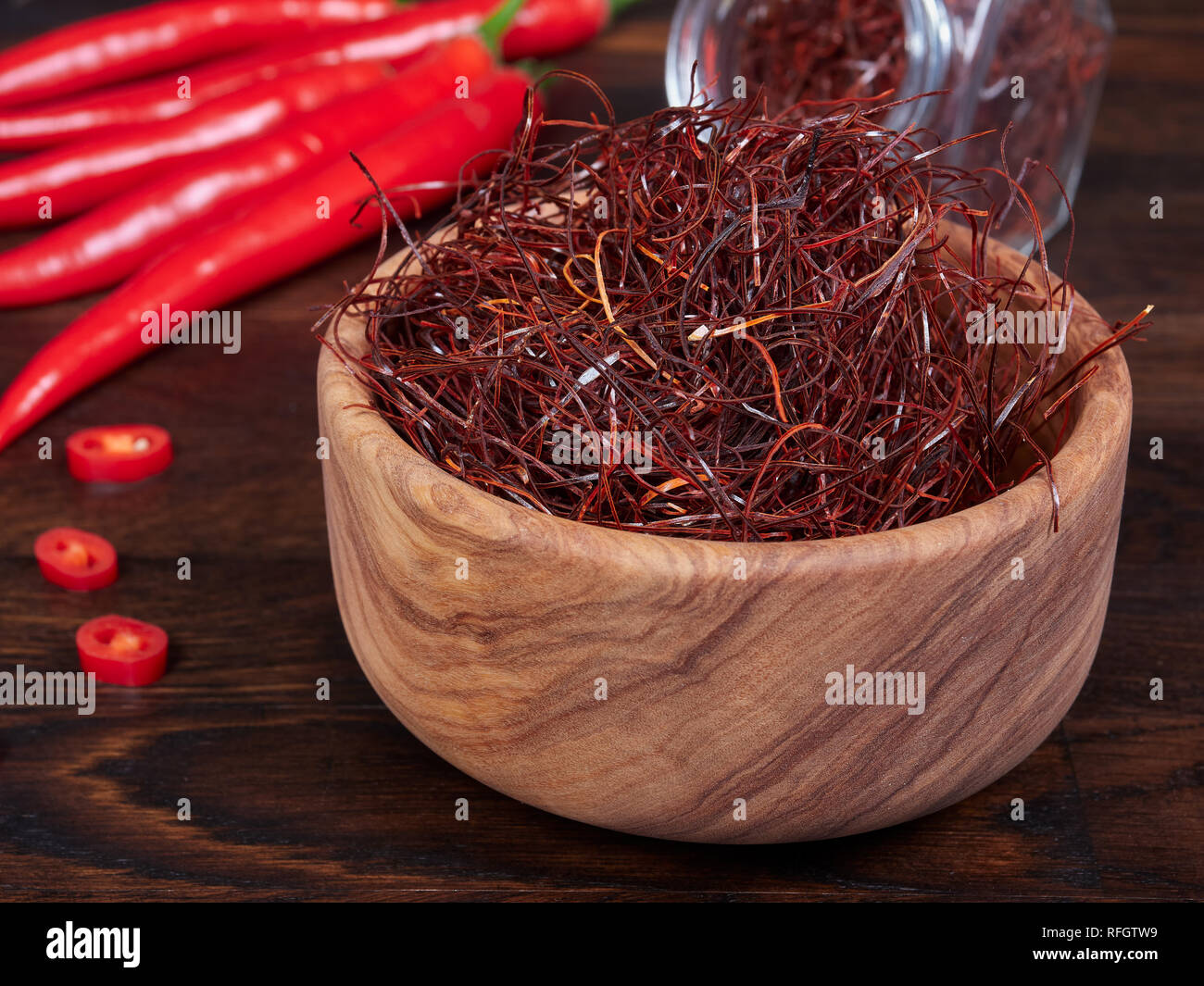 An olive wood bowl filled with thin threads of sun-dried red chili also ...