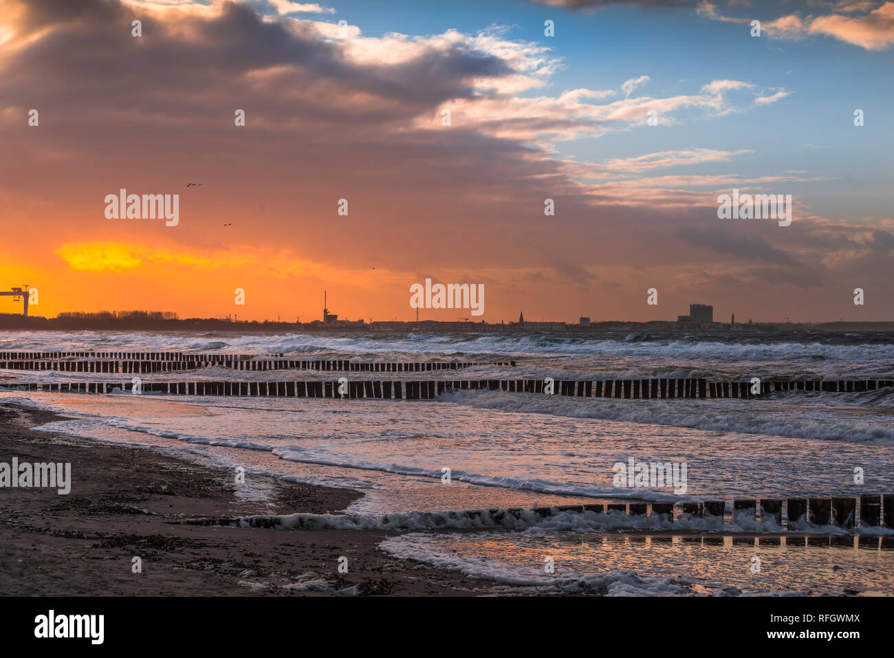 Sonnenuntergang am Strand von Markgrafenheide mit Blick Richtung Warnemünde am Neujahrstag bei Sturm Stock Photo