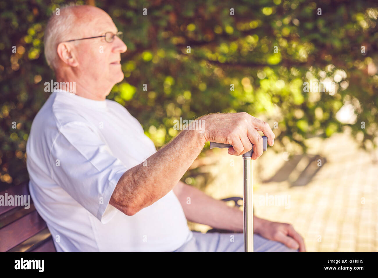 Close up hands of old man with his walking stick in the park Stock Photo