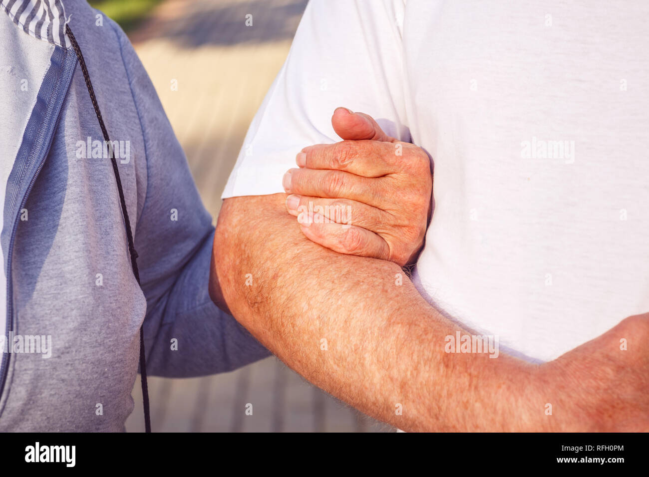 Hands of senior couple during walk in park on sunny day close up- Happy together Stock Photo