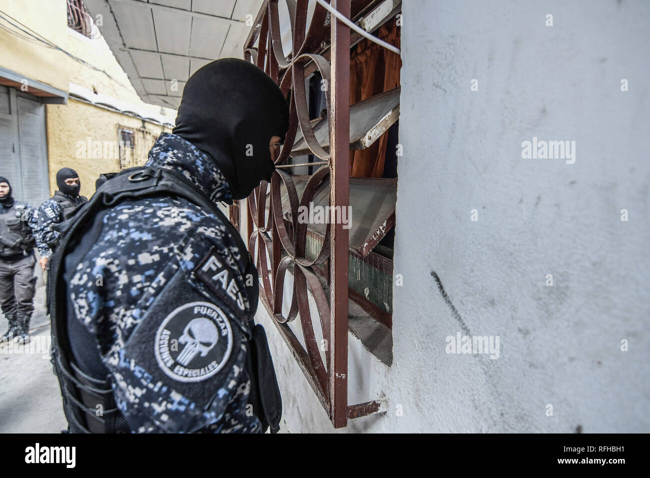 Caracas, Venezuela. 25th January 2019. A member of the Bolivarian National Police Special Forces (‘FAES’ in Spanish) seen looking through a window while taking position during a Police raid operation against criminal groups at Petare slum in Caracas. Credit: SOPA Images Limited/Alamy Live News Stock Photo