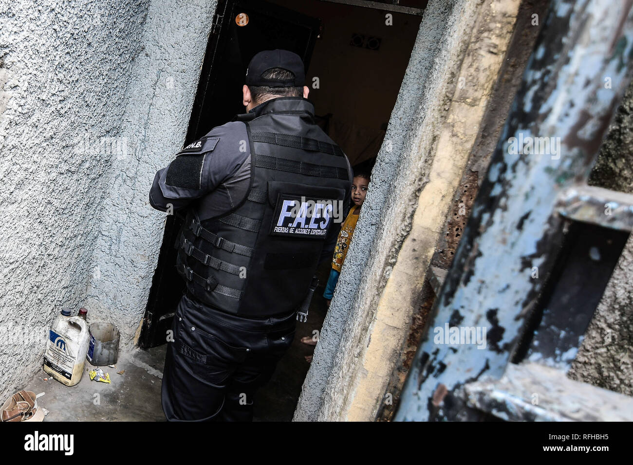 Caracas, Venezuela. 25th January 2019. A member of the Bolivarian National Police Special Forces (‘FAES’ in Spanish) seen speaking to a little kid during a Police raid operation against criminal groups at Petare slum in Caracas. Credit: SOPA Images Limited/Alamy Live News Stock Photo