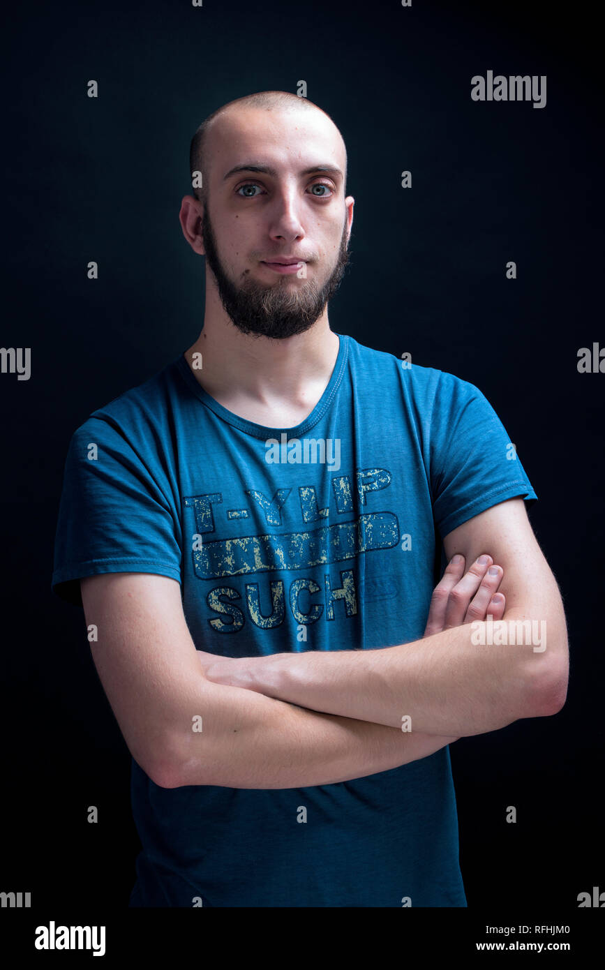 Portrait of young male in his 20s looking straight to the camera. Studio shot against black background Stock Photo