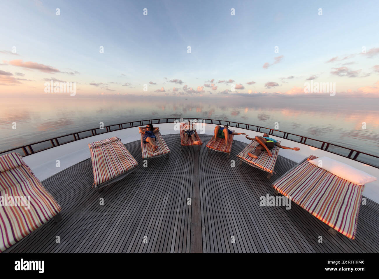 Group of people lounge on deck of boat at sunset after mapping dive Stock Photo