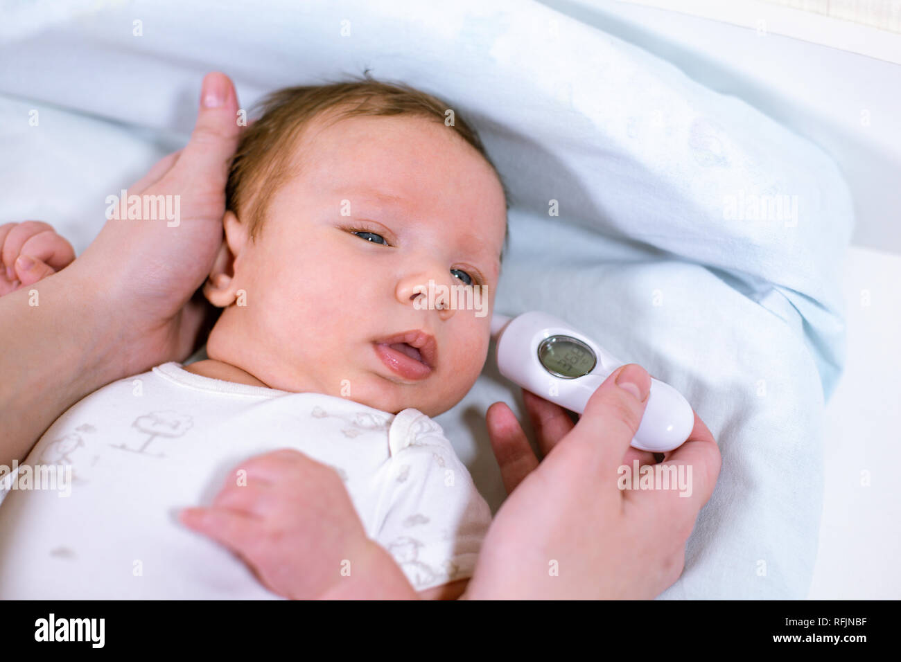 Measuring baby's temperature with contactless thermometer. Mom measures