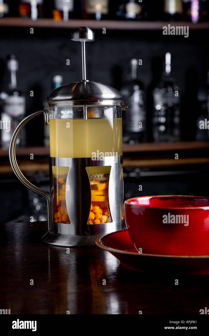 Sea buckthorn tea in french press on a bar background at coffee shop