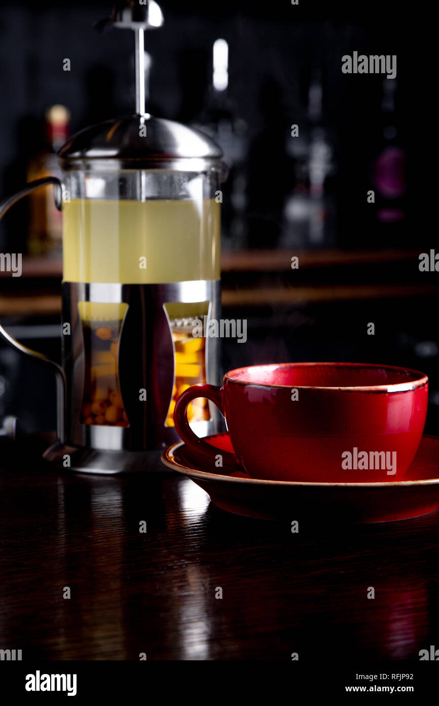 Sea buckthorn tea in french press on a bar background at coffee shop