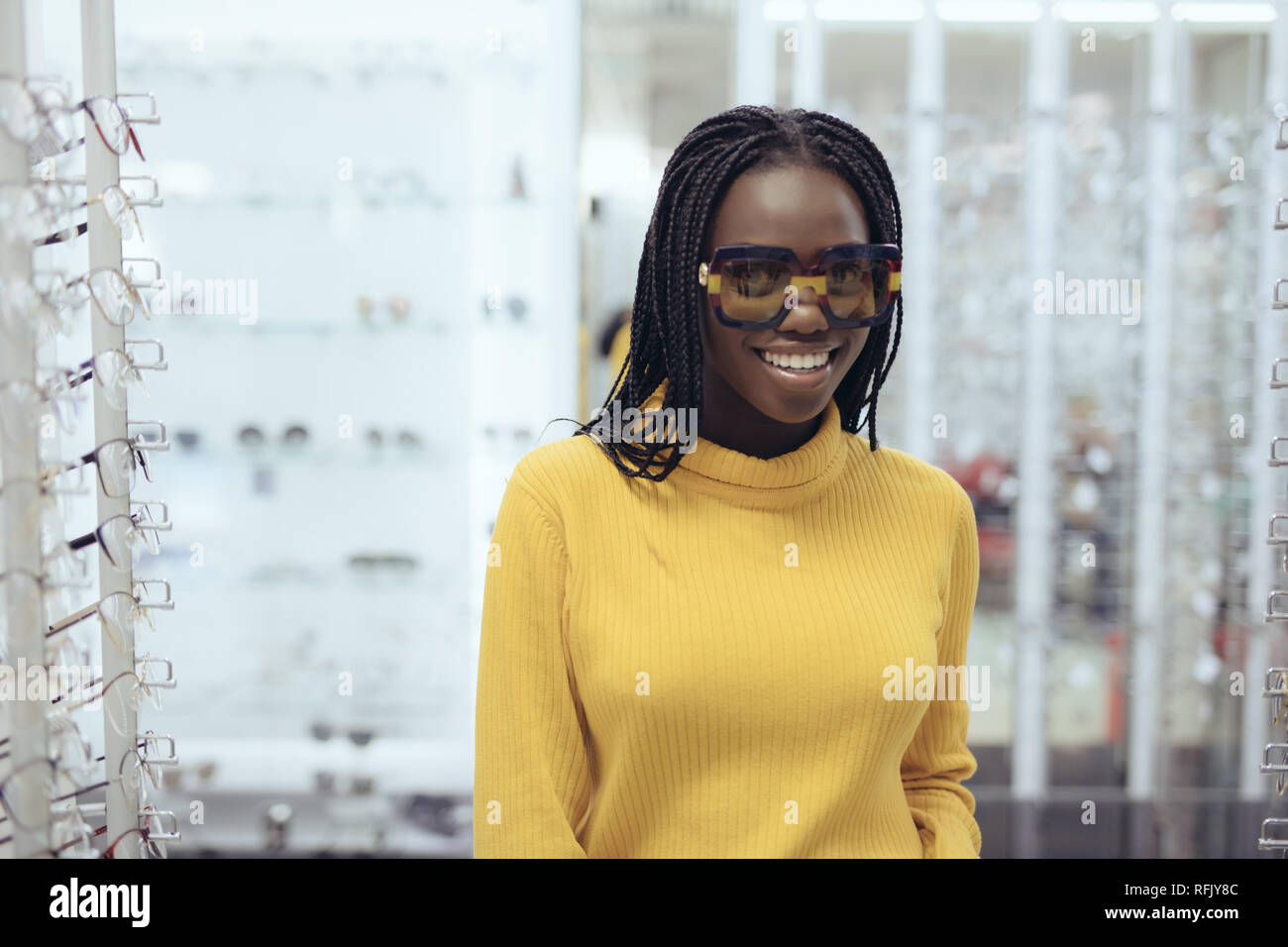 Young african woman in casual clothes try different sunglasses in