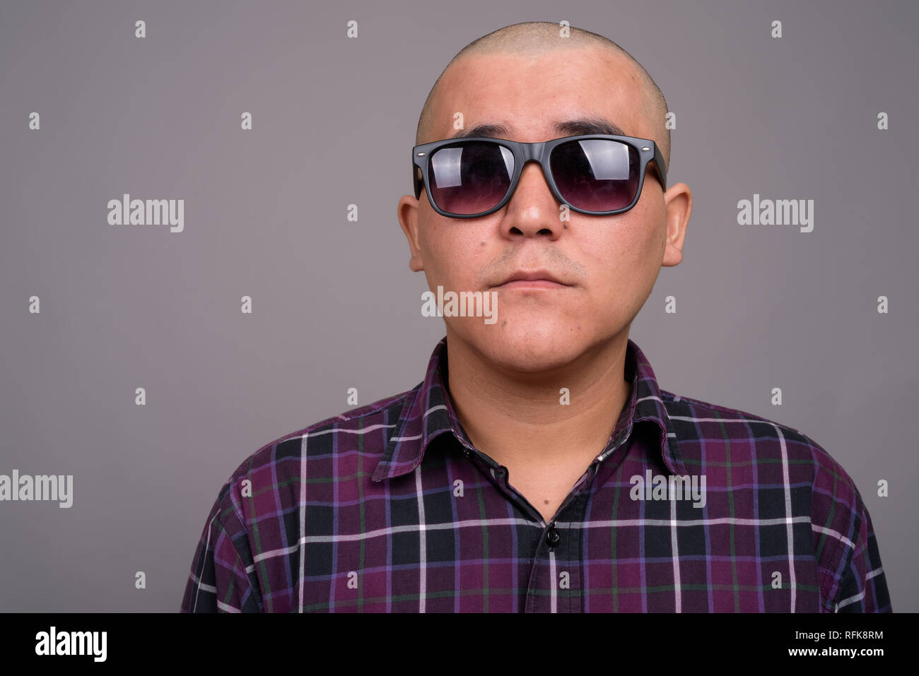 Young bald Asian businessman against gray background Stock Photo