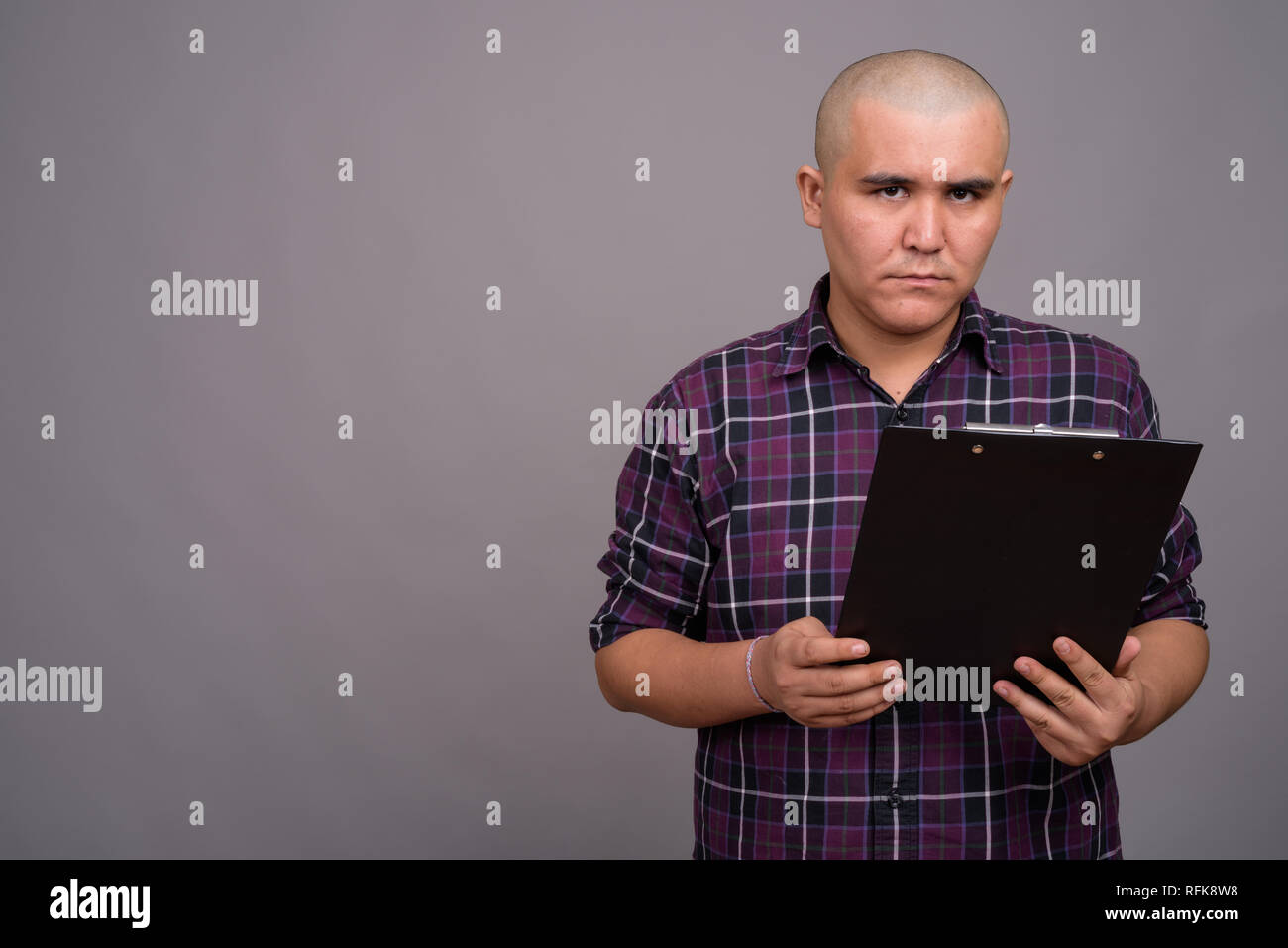 Young bald Asian businessman against gray background Stock Photo - Alamy