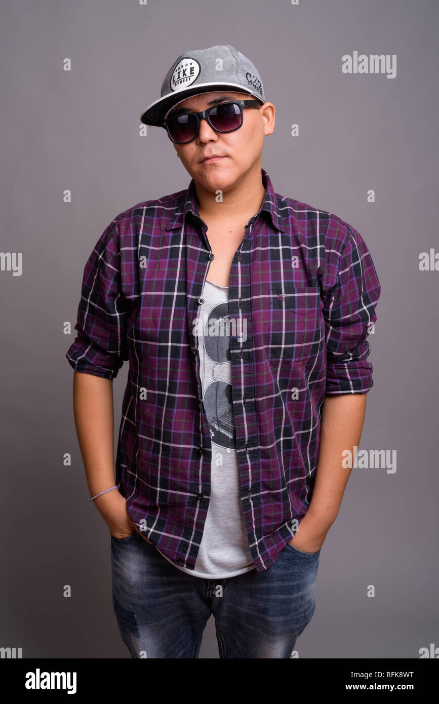 Young Asian gangster man against gray background Stock Photo - Alamy