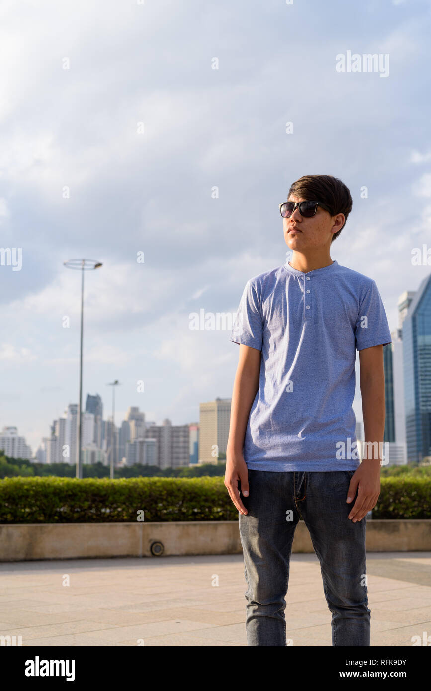 Young Asian teenage boy wearing sunglasses while relaxing at the Stock Photo
