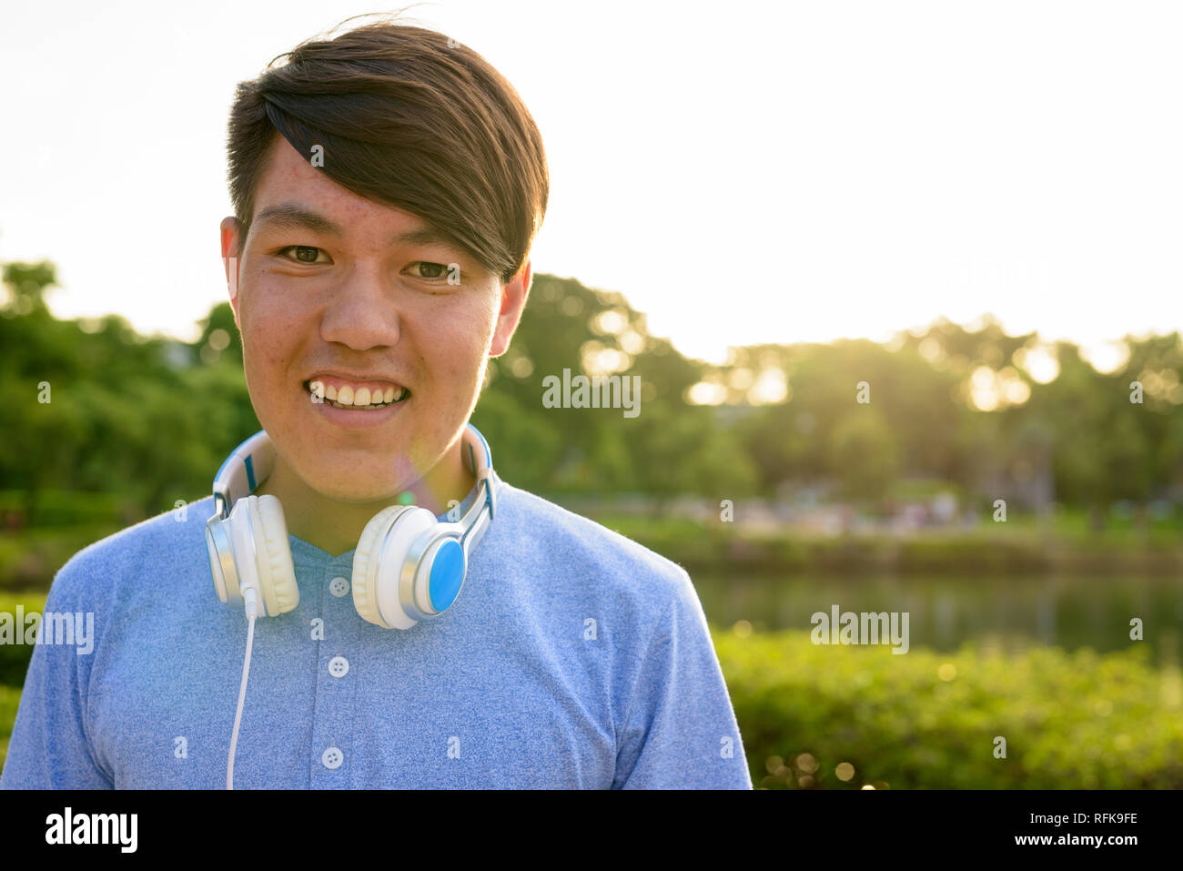 Young Asian teenage boy wearing headphones while relaxing at the Stock Photo