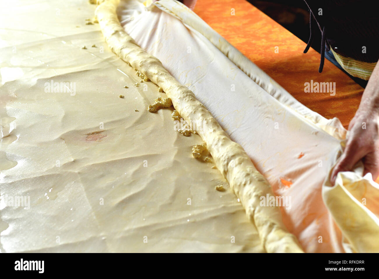 Rolling dough for strudel with curd cheese on a kitchen table Stock Photo