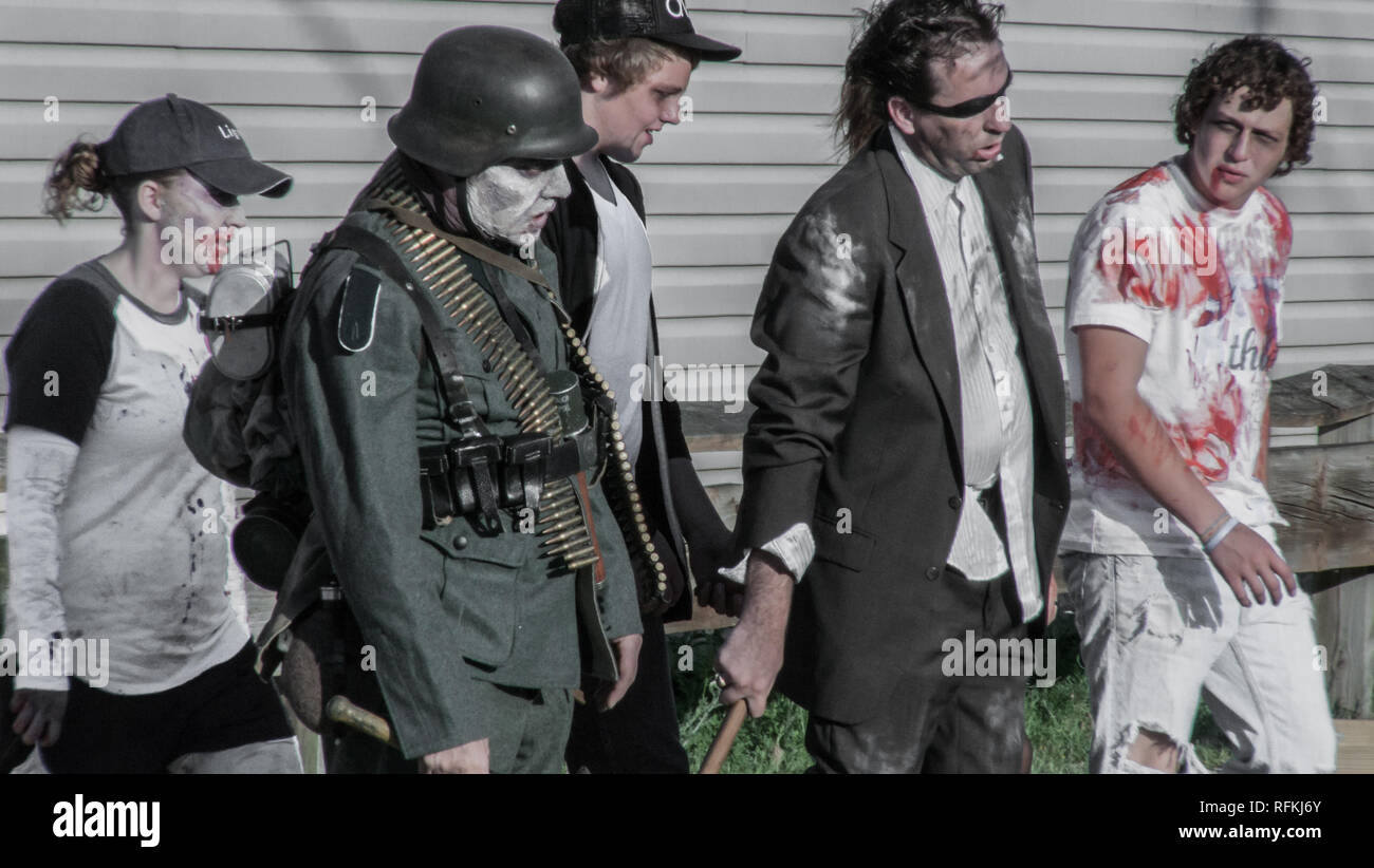 A zombie soldier and other people dressed as zombie parade the street during a June 2010 zombie walk flash mob in Michigan Stock Photo