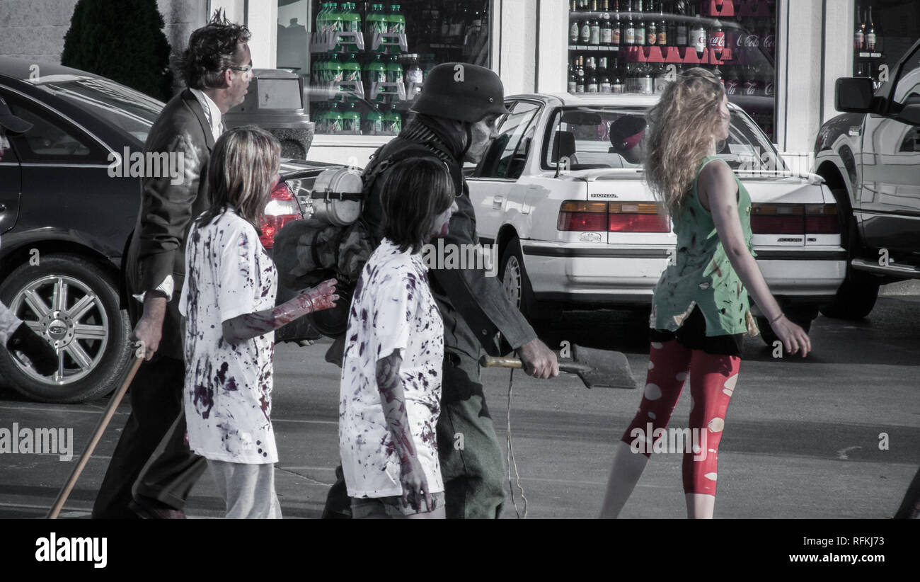 A zombie soldier and other people dressed as zombie parade the street during a June 2010 zombie walk flash mob in Michigan Stock Photo