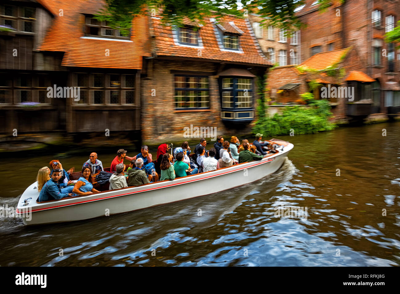 Bruges, Belgium - July 29: Canal boat tour in the Old Town of Bruges is a popular sightseeing activity. Background motion blur effect. Bruges, Belgium Stock Photo
