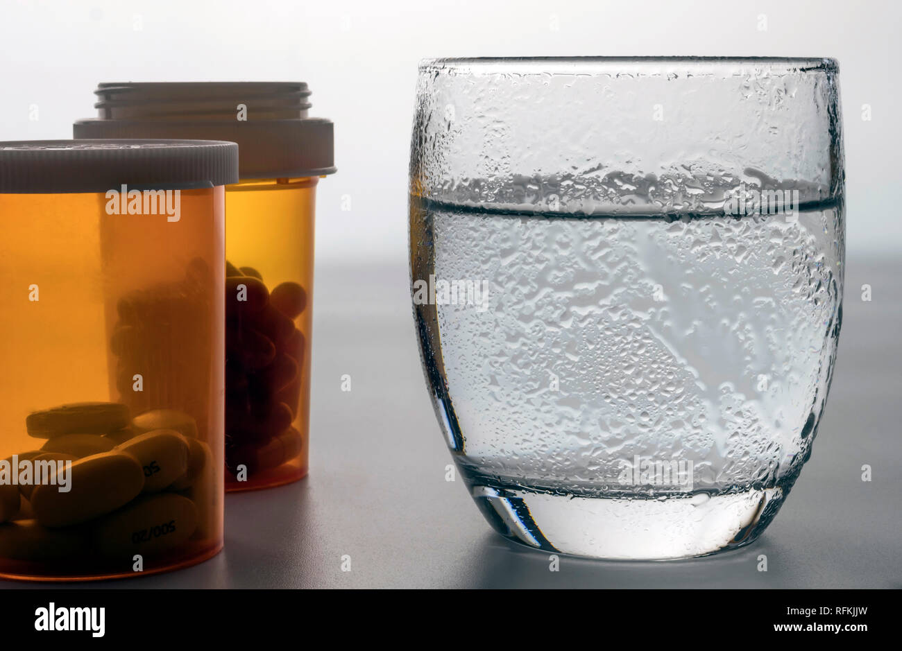 Water glass frozen along with pills, conceptual image Stock Photo