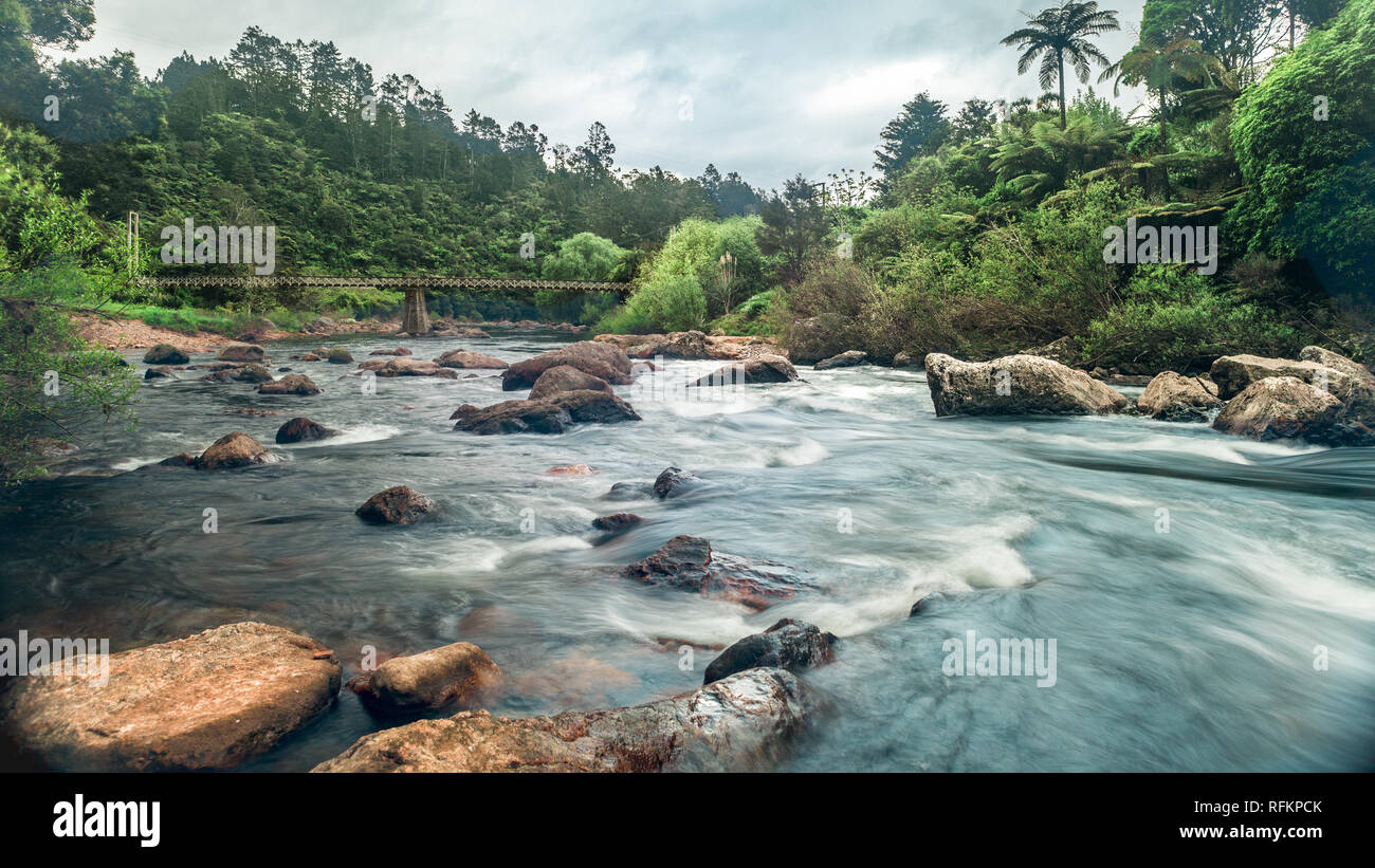The clear, fast flowing water in the Karangahake Gorge is a beautiful scene even though it is a cold cloudy overcast day. Stock Photo