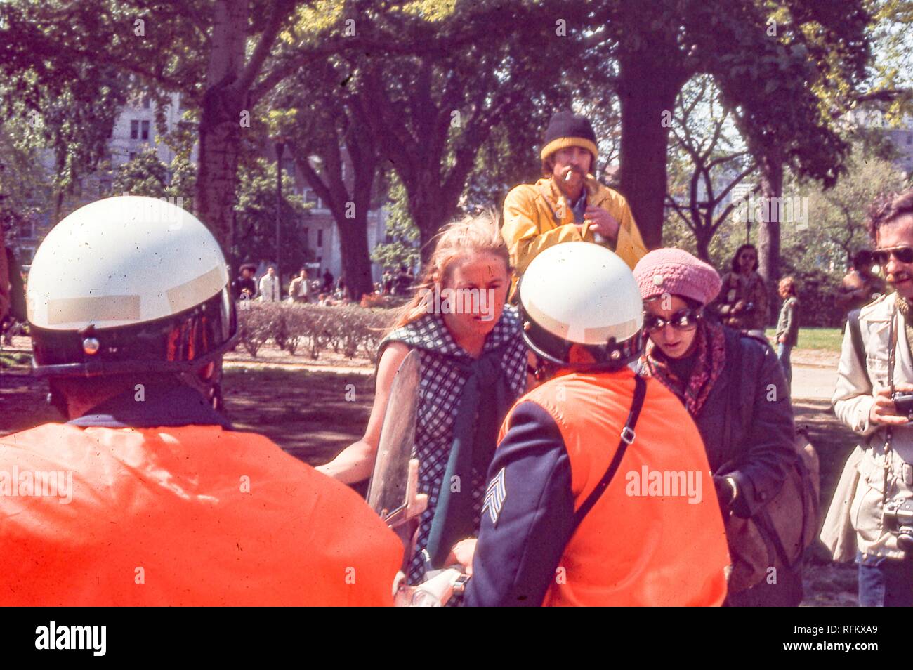 Young female protester in hippie attire confronts police officers during the May Day protests