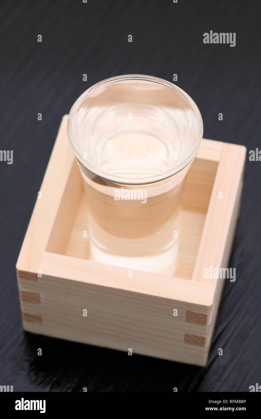 Japanese wooden box masu with sake on a wooden table background Stock