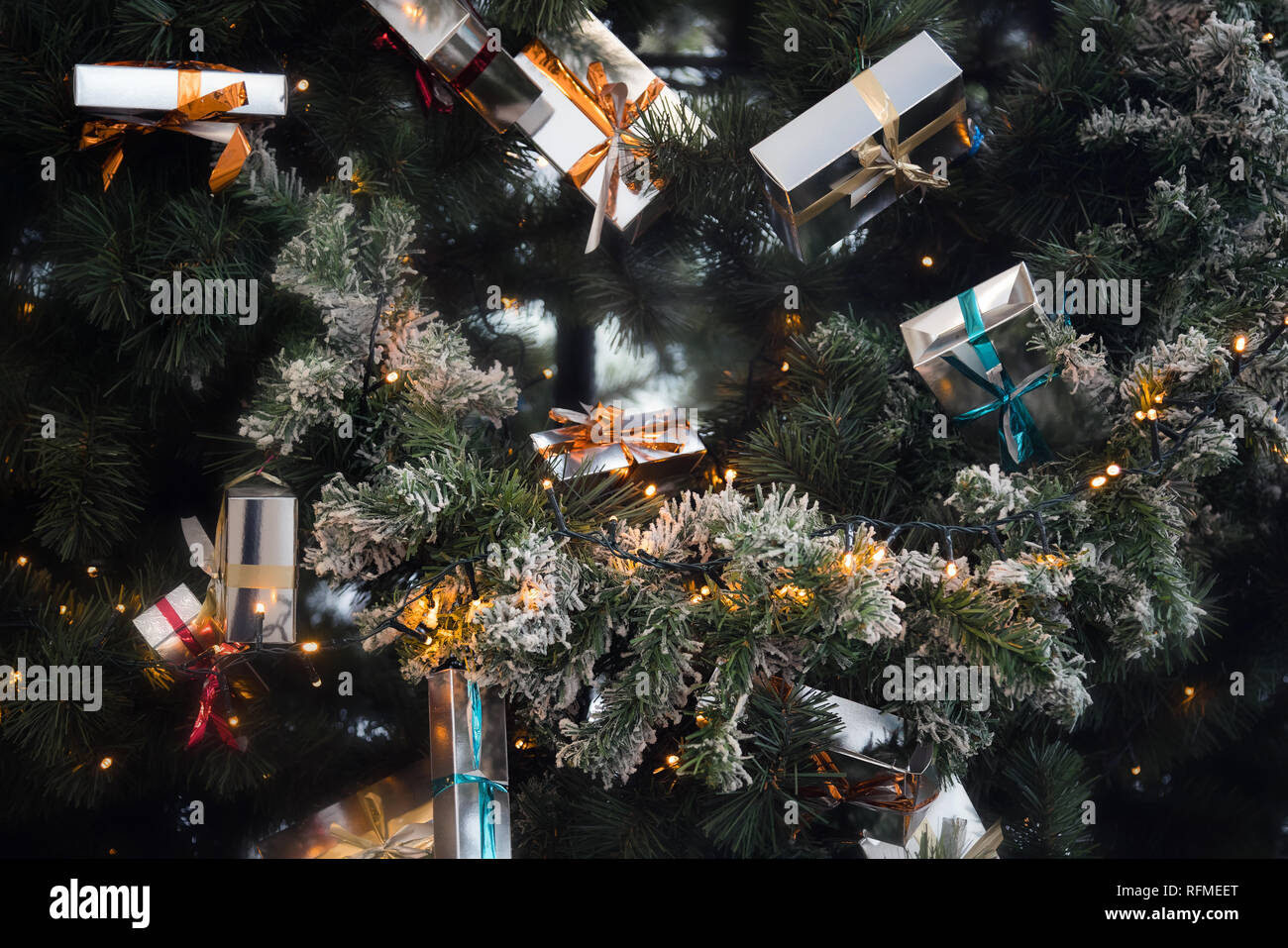 Christmas presents with ribbons in boxes hanging on festive Christmas tree Stock Photo