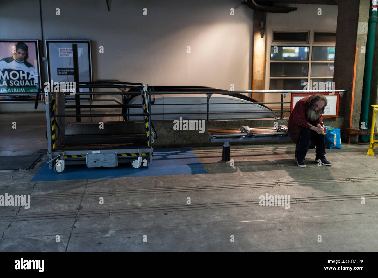 Paris, France - may 27, 2018: Anti soccial homeless sitting on the bench in railway station Montparnass. Stock Photo
