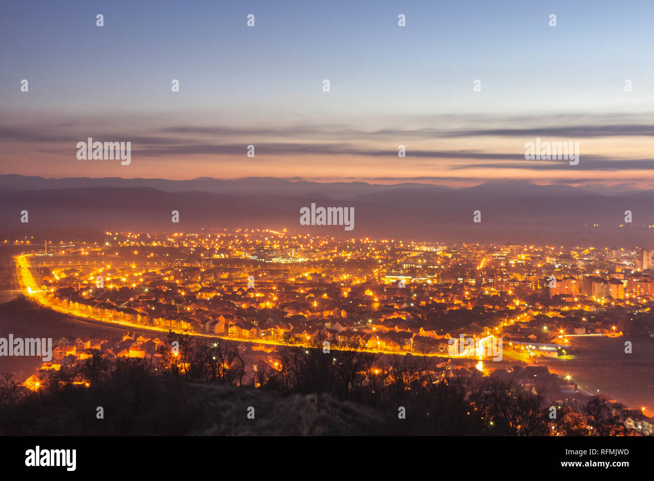 Stunning late blue hour view of Pirot cityscape with hot city lights and colorful sky Stock Photo