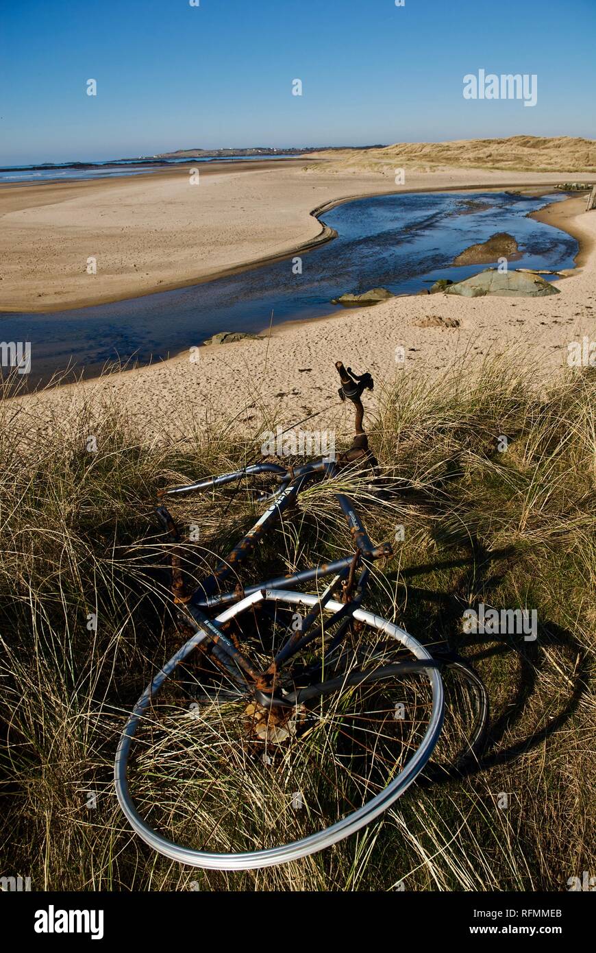 A broken bicycle discarded on a beautiful sandy beach in Rhosneigr, Anglesey, North Wales, UK Stock Photo
