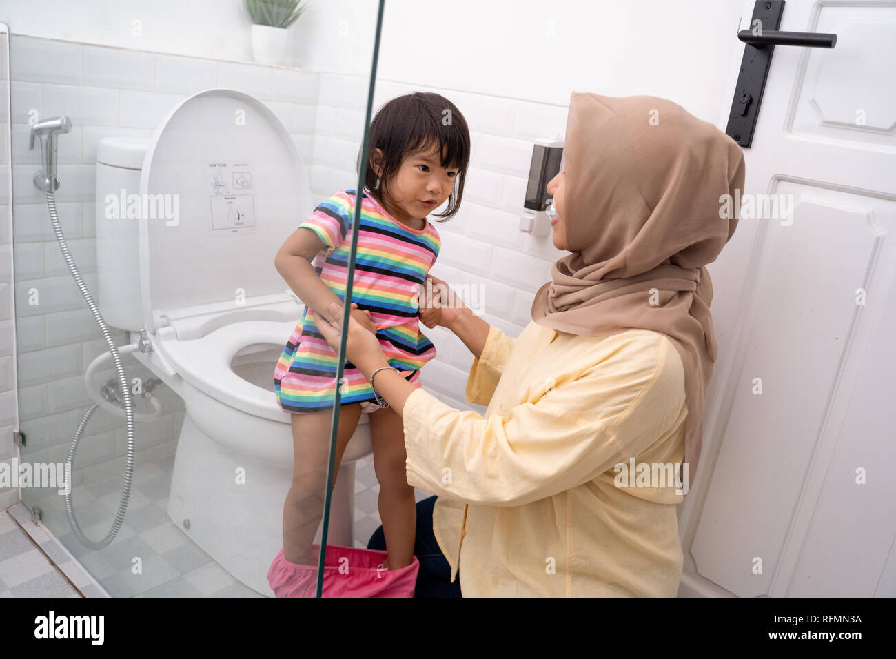 muslim mother help her kid to use toilet Stock Photo