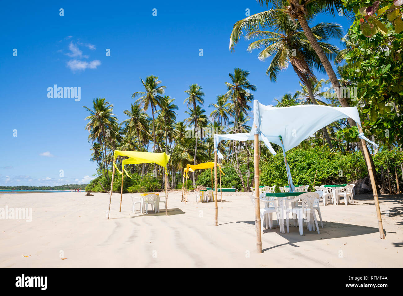 Bright scenic view of rustic handmade palapa tents standing on the sunny shore of a deserted Brazilian beach in Bahia, Brazil Stock Photo