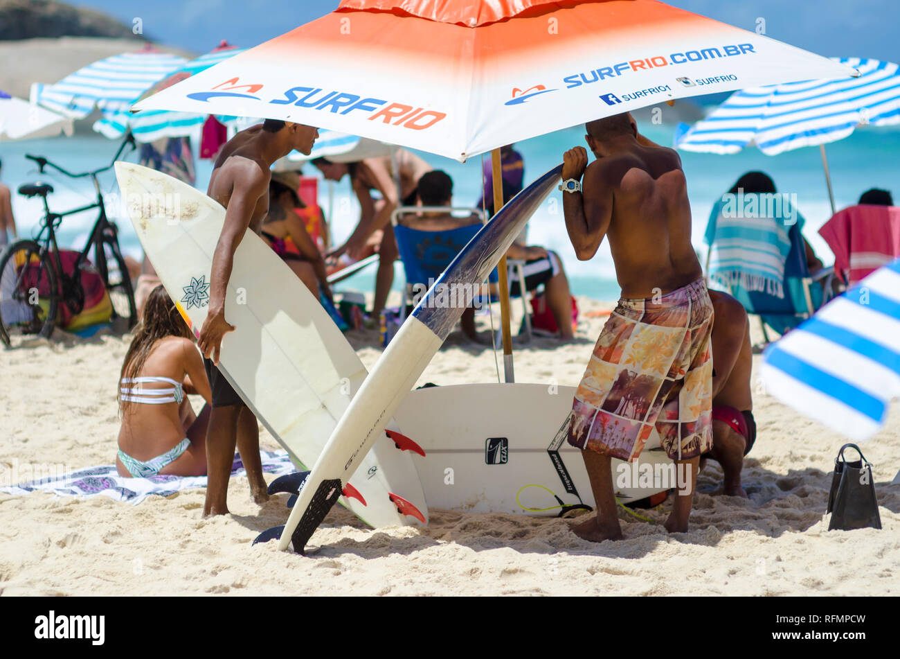 RIO DE JANEIRO - FEBRUARY 9, 2017: Young Brazilian surfers prepare their surfboards for a busy day of rentals at the Arpoador surf beach at Ipanema. Stock Photo