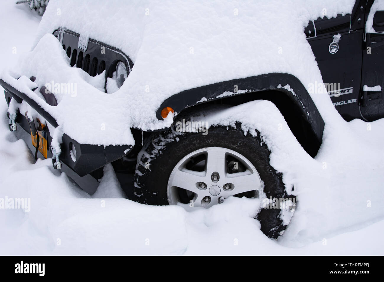 A black Jeep Wrangler Sport covered with snow after a blizzard in Speculator, NY USA Stock Photo