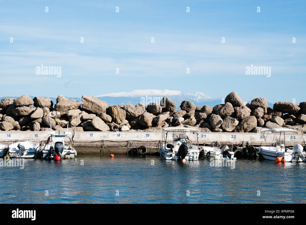 The boat harbour in Diakopto with snow capped mountains in the background Stock Photo