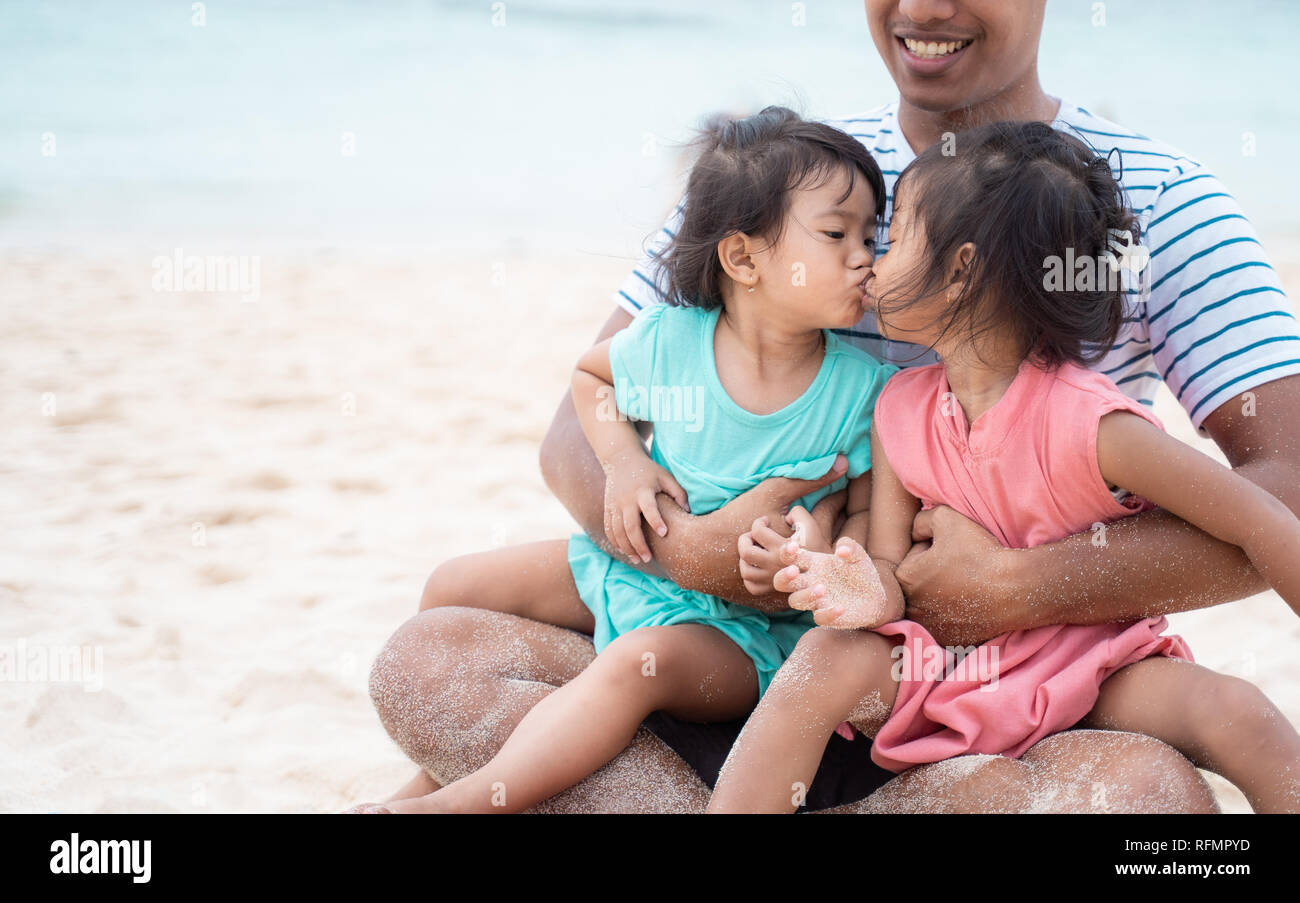 two little girls kissing each other when on dad's lap Stock Photo - Alamy