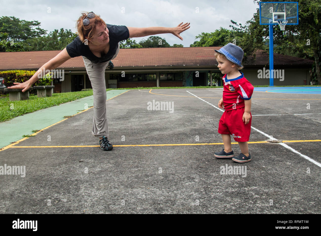 A woman and a young boy in a football outfit are working out on a basketball court Stock Photo