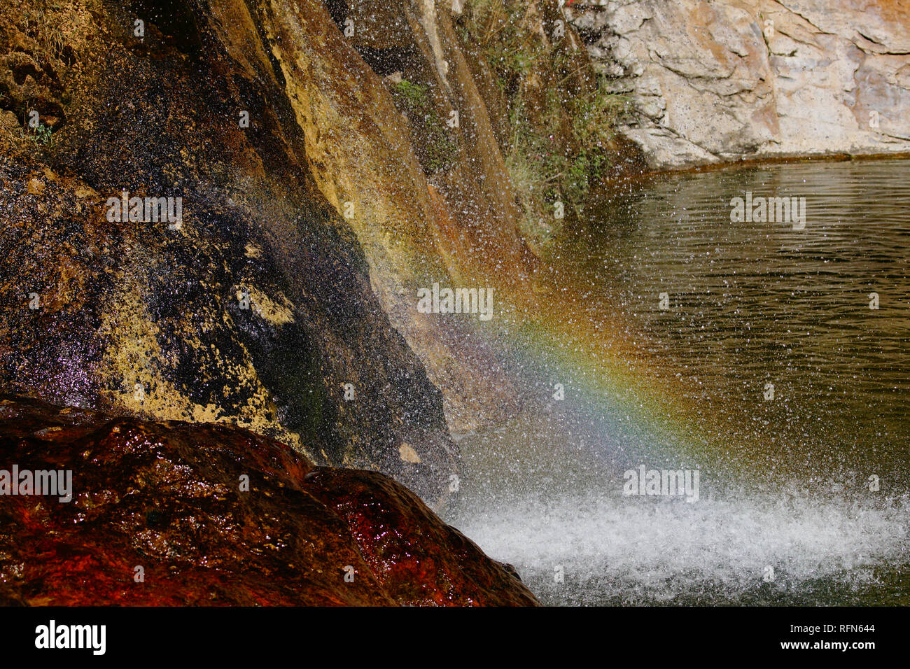 At the base of a waterfall a rainbow can be seen. Stock Photo