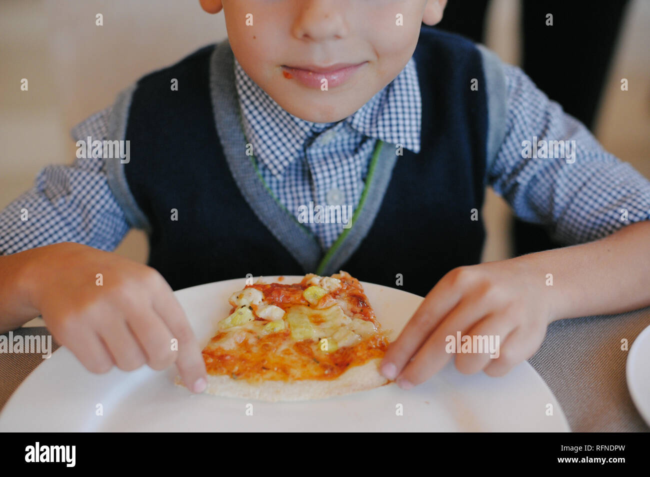 happy little boy holding and eating pizza in cafe Stock Photo - Alamy