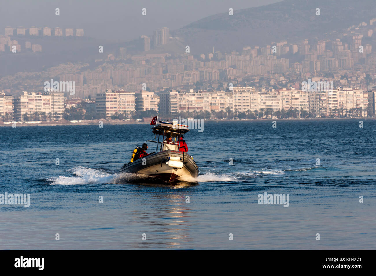 Policemen on a rubber dinghy going fast on the seawater in front of ...