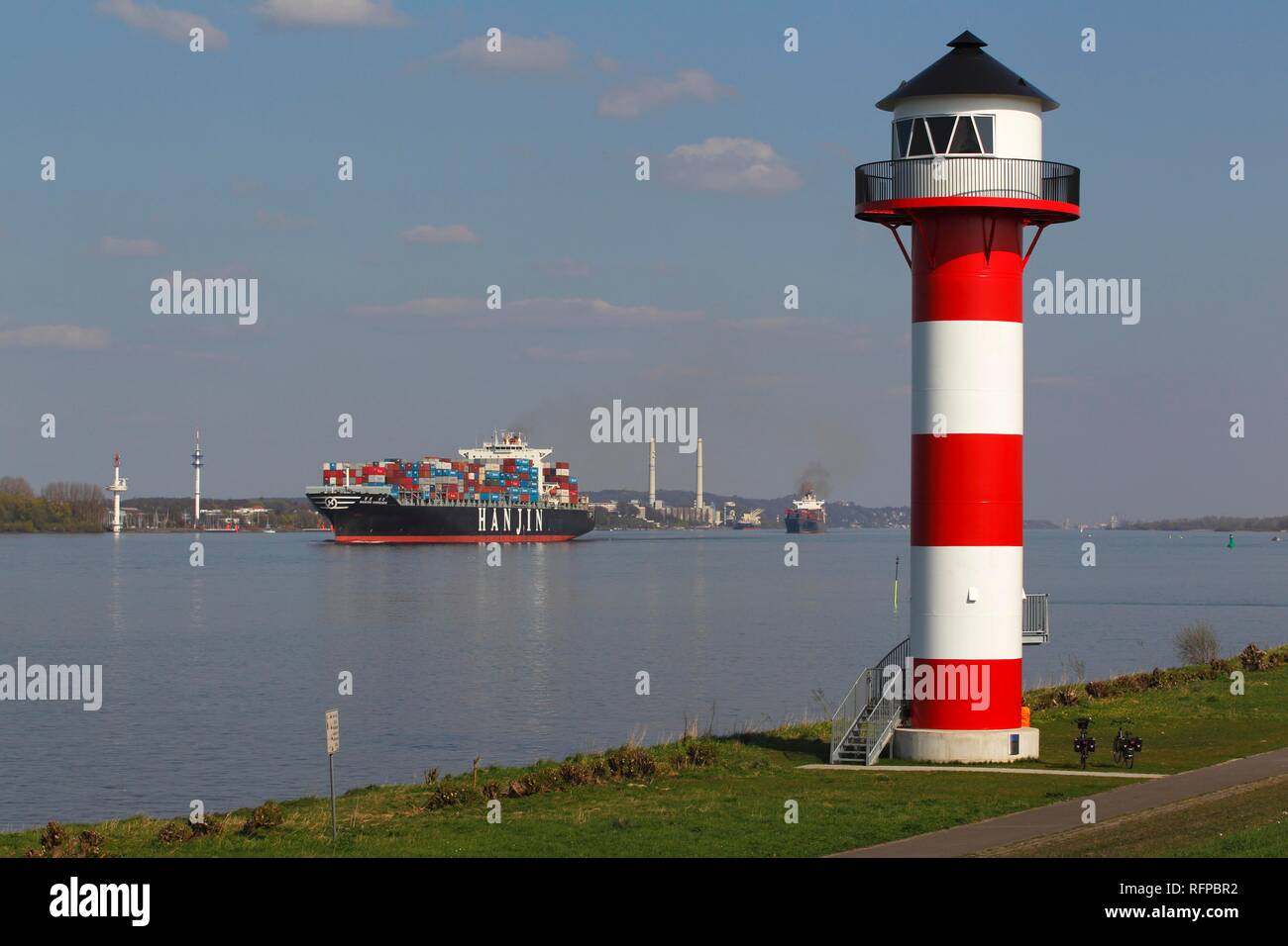 Container ships on the Elbe River pass lighthouse, front light Somfletherwisch, Lühe, Altes Land, district of Stade Stock Photo