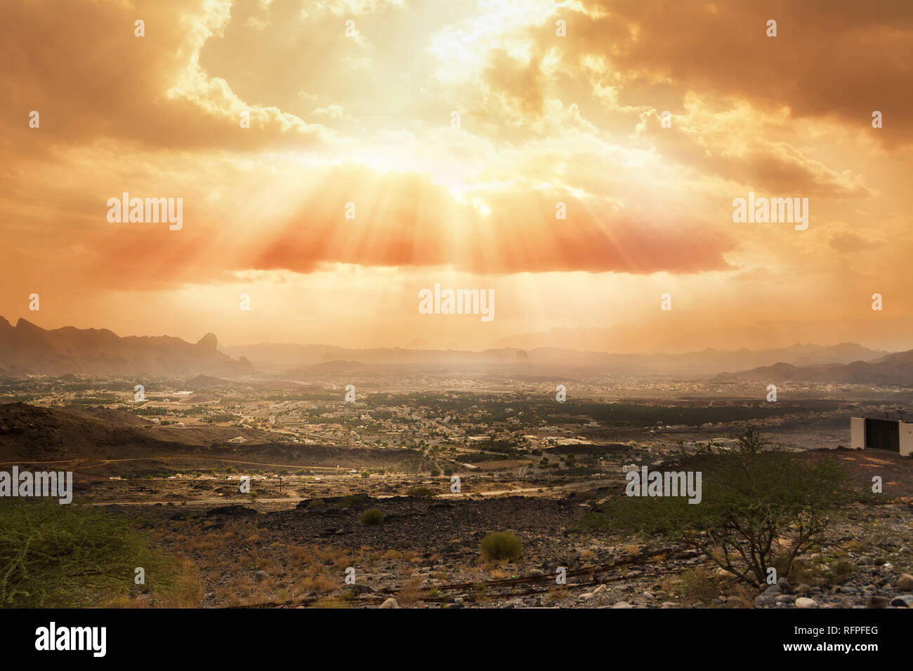 Cloudy sky slashed by the sun's rays over the village of Al Hamra (Oman) Stock Photo