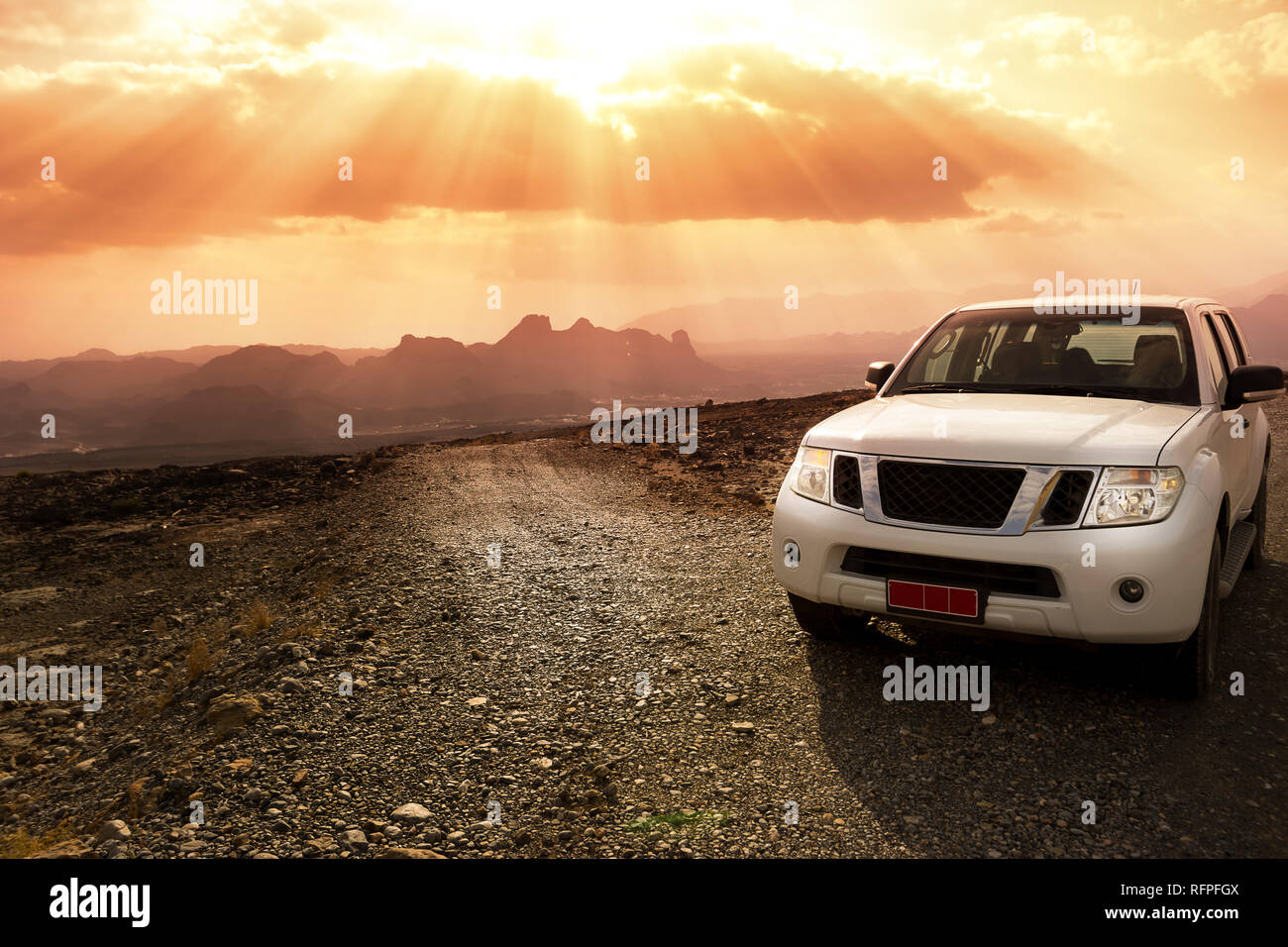 Off-road vehicle on the Jebel Shams mountains and cloudy sky with amazing sunrays Stock Photo