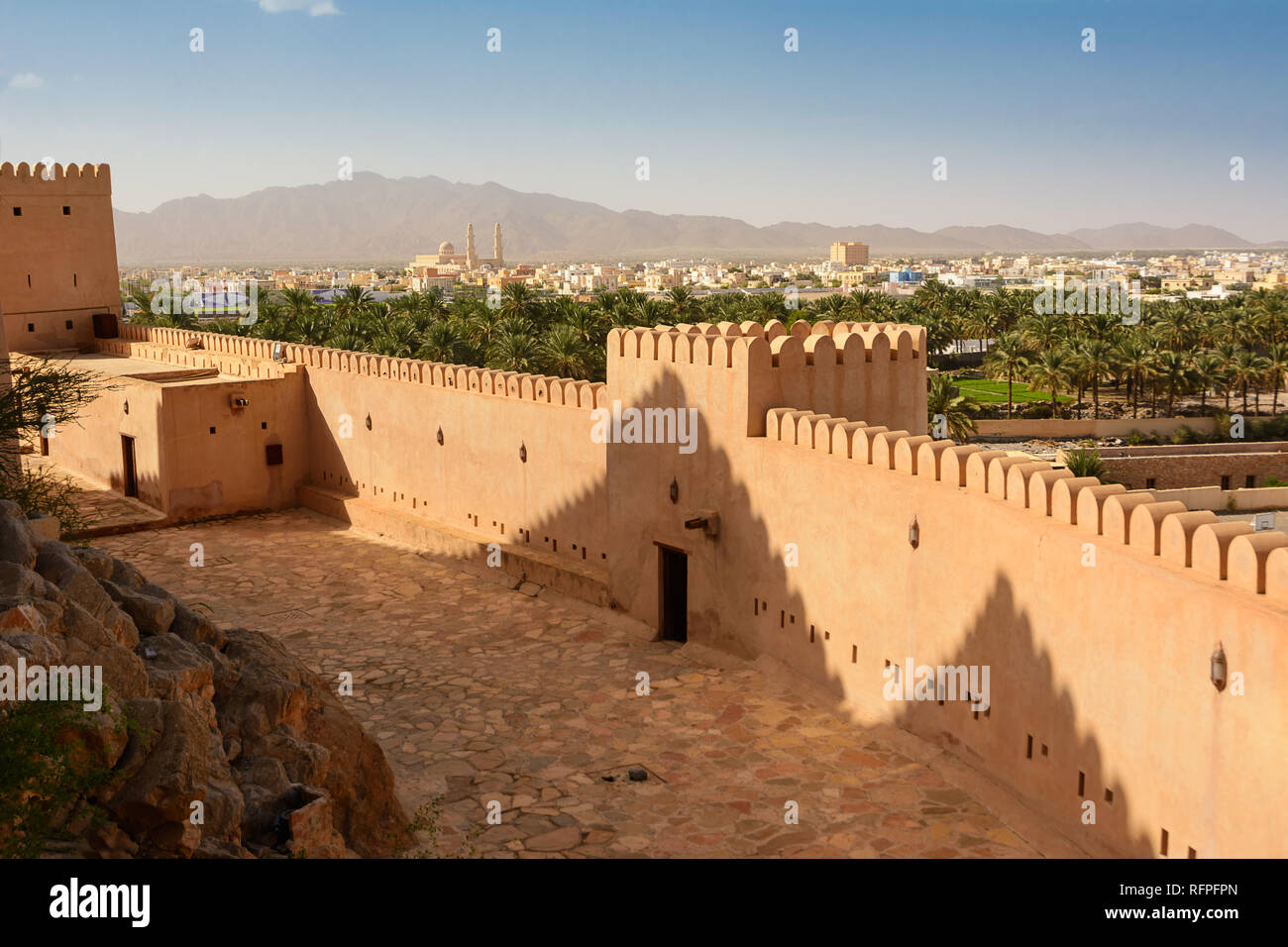 Walls of the Fort of Nahkal and the village with the mosque in the background (Oman) Stock Photo