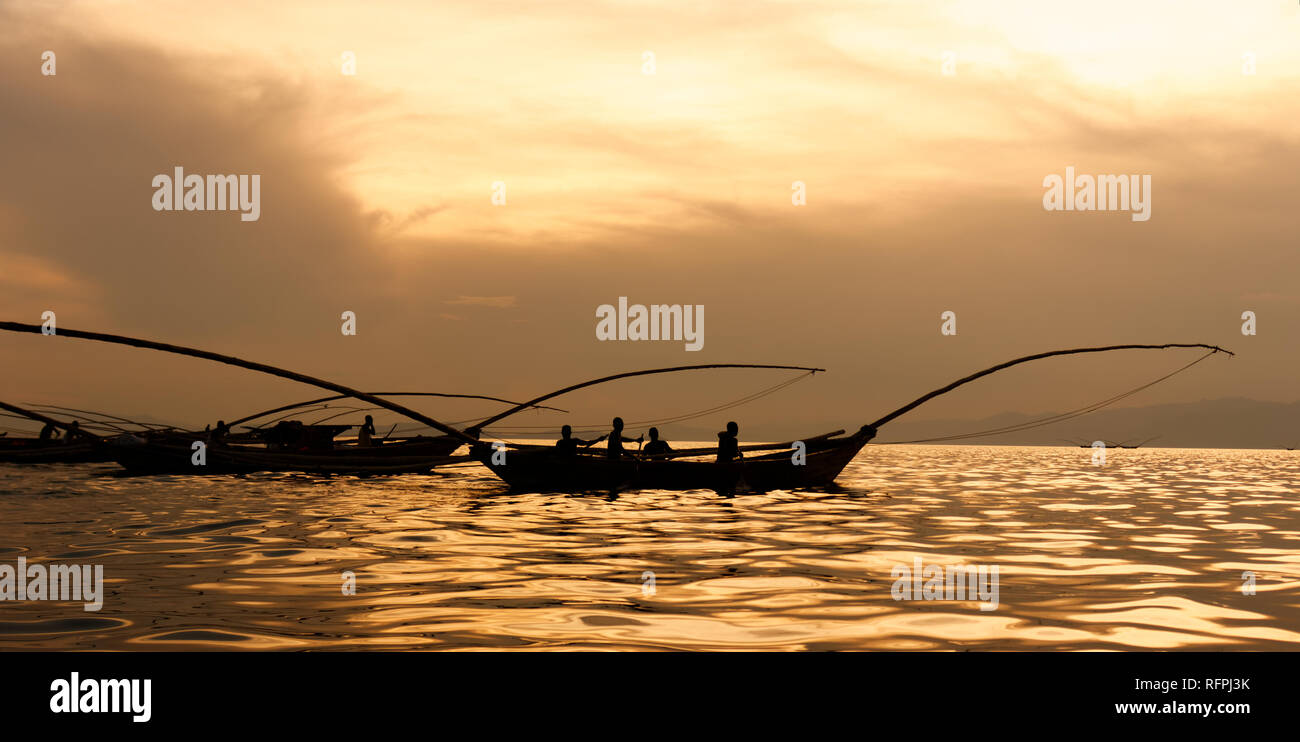 Golden sunset with traditional fishing boats on Lake Kivu, Rwanda. Silhouettes of boats and fishermen - sunlight on water. Stock Photo