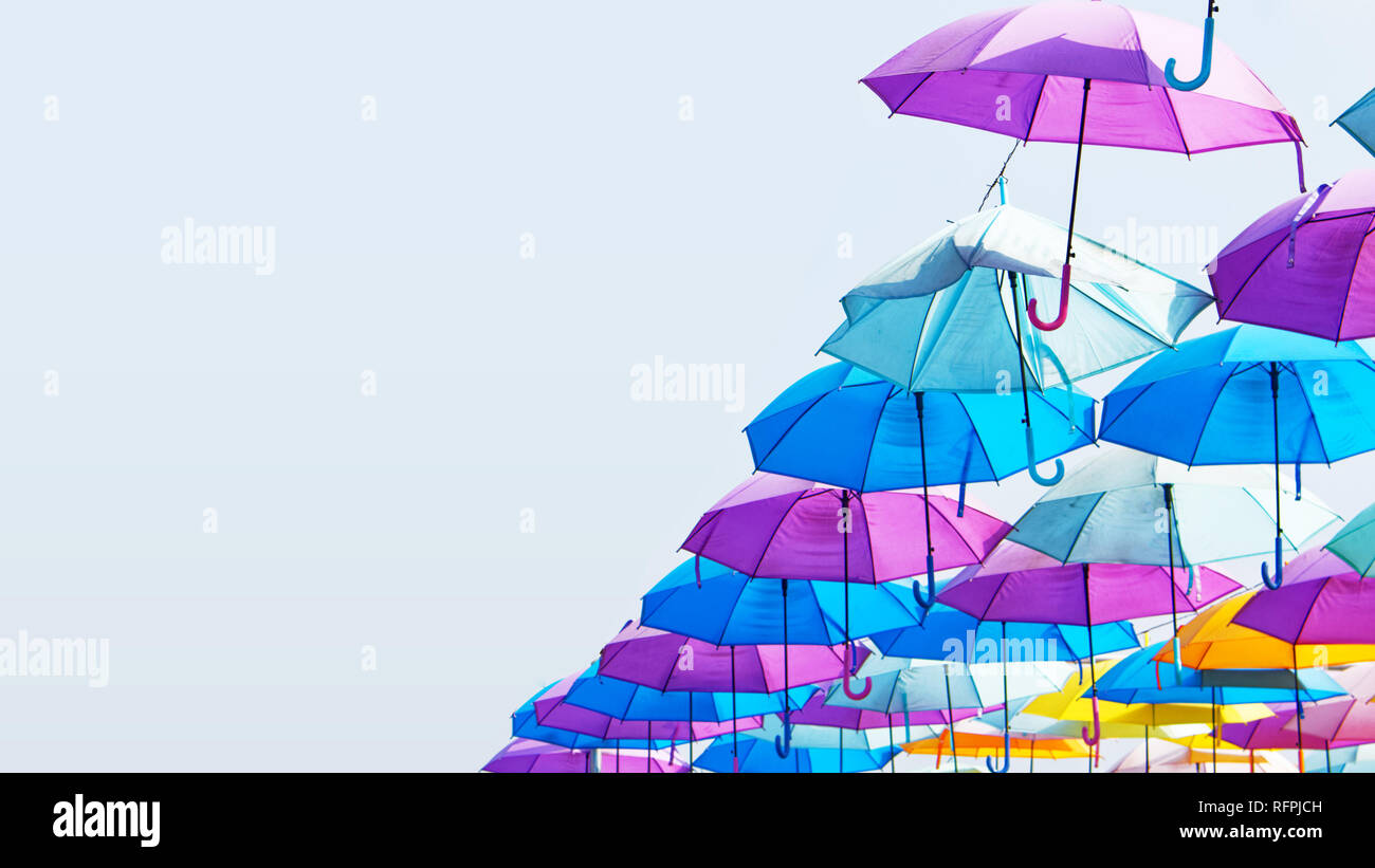 Colourful umbrellas hanging in the sky; Vibrant multicolor street art scene background with copy space Stock Photo