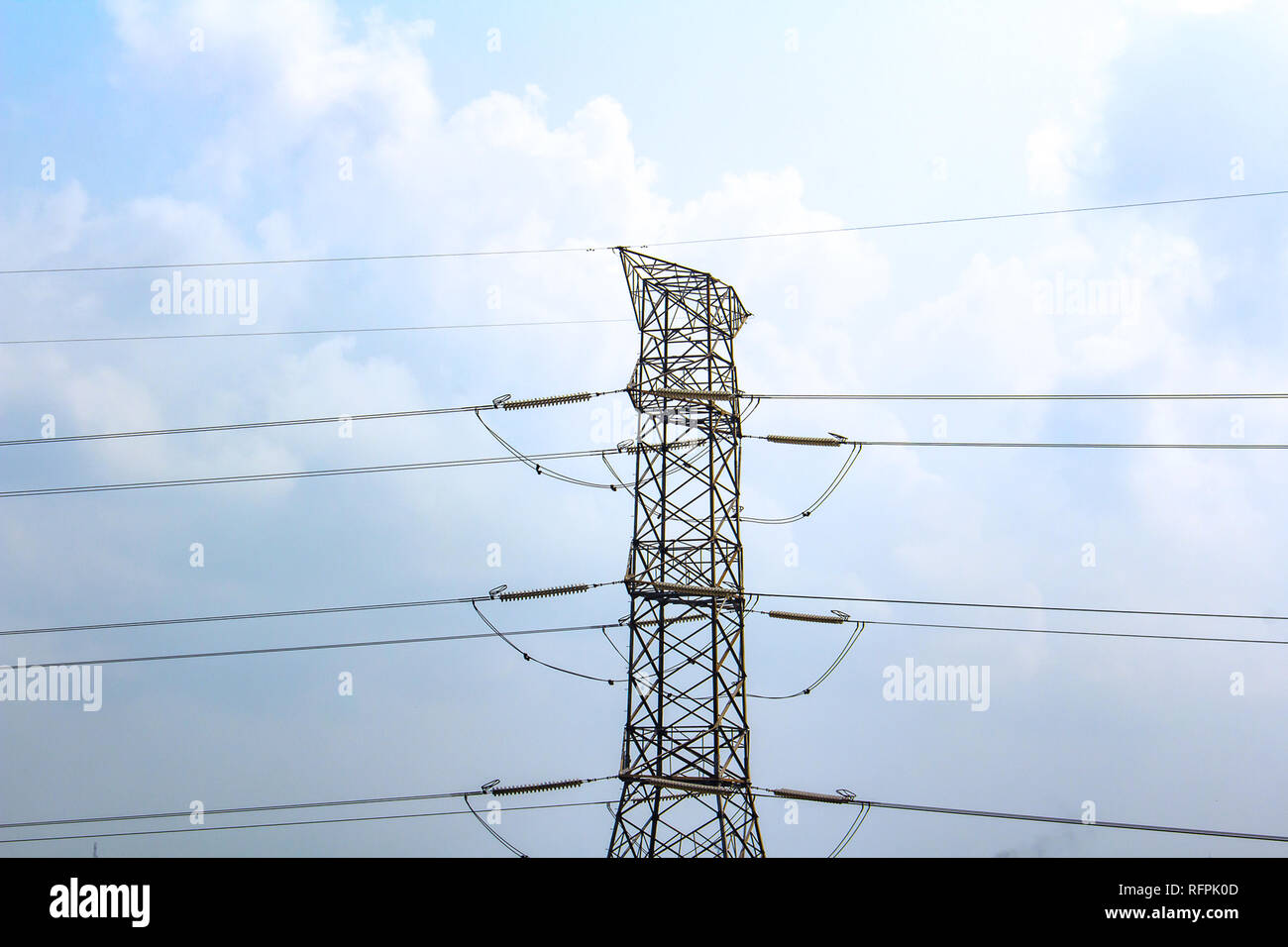 High-voltage electric power lines against a blue sky with white clouds Stock Photo