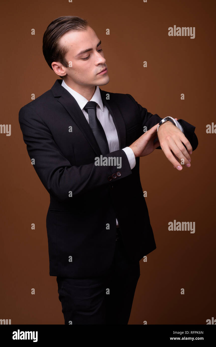 Portrait of young Caucasian businessman checking time from watch Stock ...